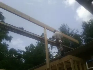 Carpenter setting a ridge beam over a new addition frame — Ice Dam Removal by Roofing Brothers in Lake Jackson