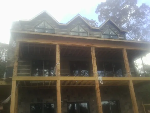 Dormers and porch framing on a large log home under construction — Roof Coating work by our crew in Lake Jackson