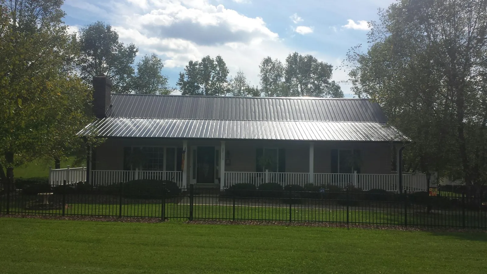 Gray metal roof on a brick ranch with a full width front porch — Gutter Guard Installation work by our crew in Lake Jackson