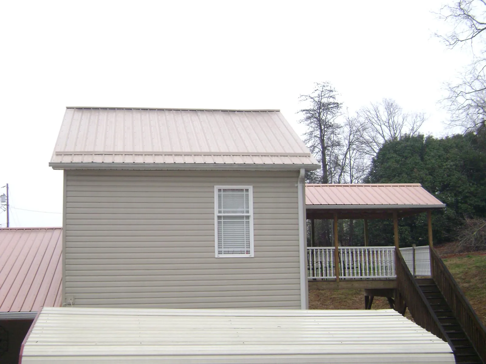 Tan metal roofs on a two story addition and attached porch, from a Roof Replacement job in Lake Jackson