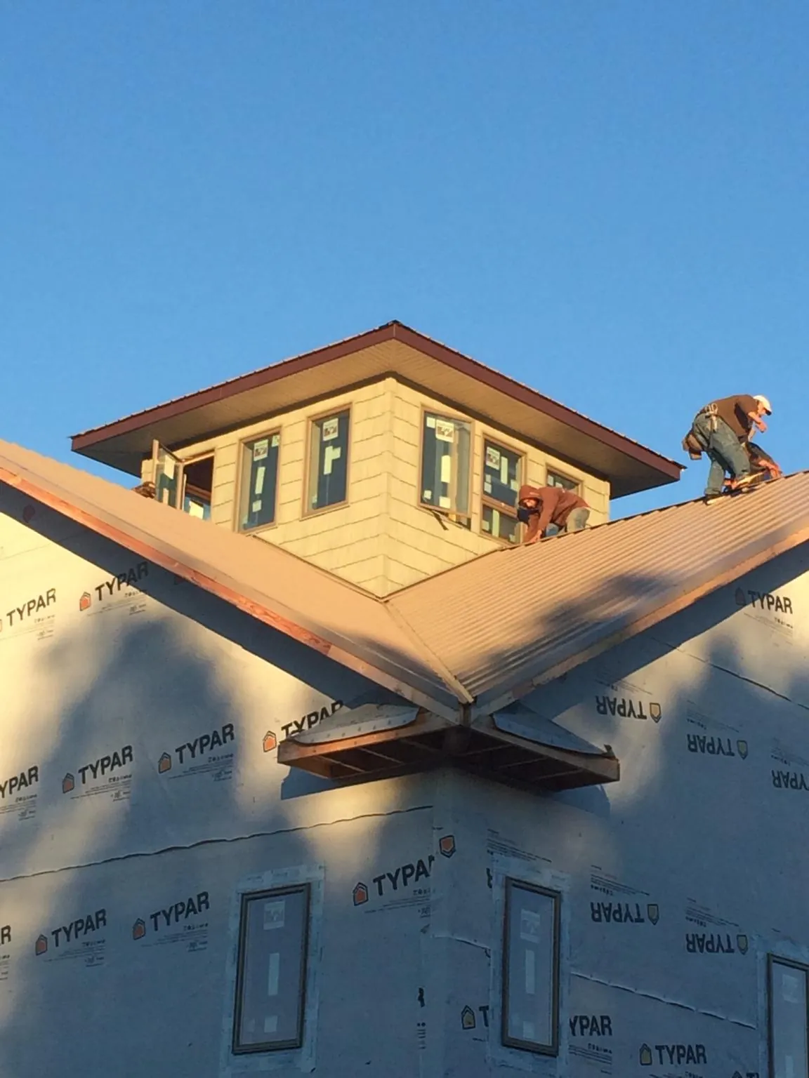Roofers working around a rooftop cupola on a new metal roof at sunset — Roof Waterproofing in Lake Jackson by Roofing Brothers